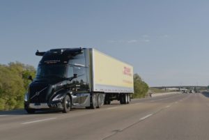 A semi-truck with a black cab pulling a yellow trailer bearing "DHL" in red lettering across the side