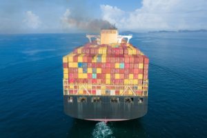 A CONTAINER SHIP AT SEA SPOUTS GREY SMOKE INTO THE SKY
