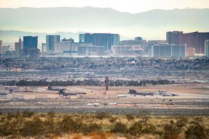 PLANES SIT ON THE TARMAC IN A DESERT AIRPORT, FRAMED BY A CLUSTER OF MODERN TOWERS BEHIND